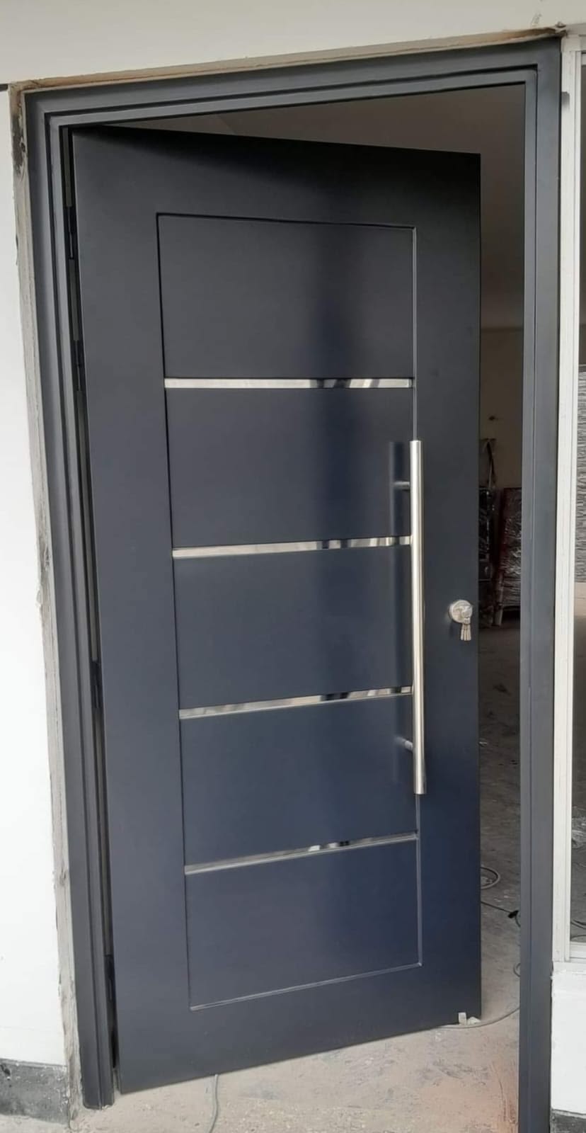 Grey steel entrance door with vertical inlay detailing, installed on site