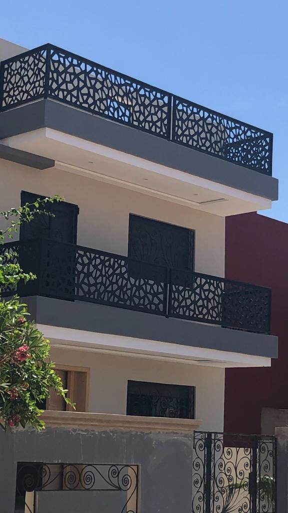 Laser-cut metal balcony railing panels installed across the front elevation of a building