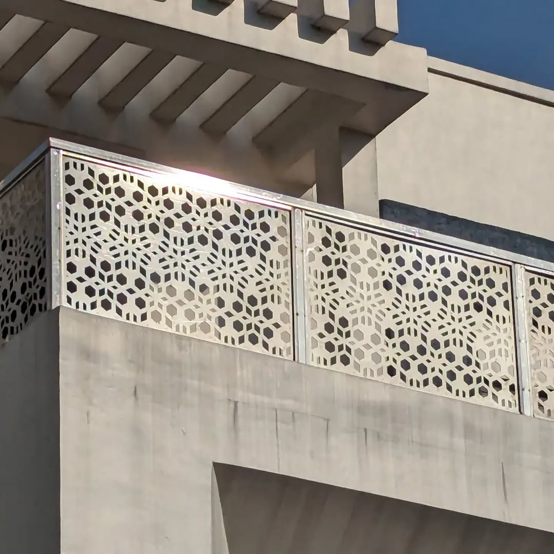 Laser-cut balcony infill panels installed along a concrete parapet